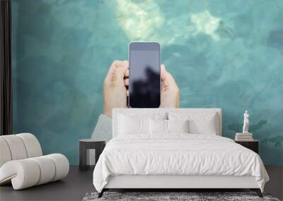 girl holding a blank cell phone on the background of water Wall mural