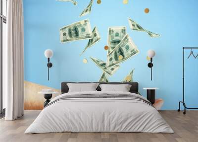 Human hand with money and coins falling at blue background Wall mural