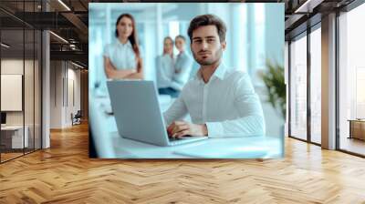 Young man in white shirt working on laptop with colleagues in the background, professional office setting, concept of teamwork. Generative AI Wall mural