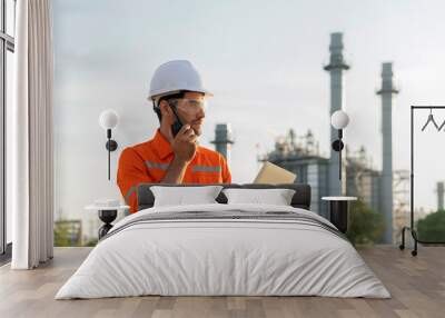 male caucasian engineer technician Industrial workers wearing safty uniform with walkie-talkie and laptop working inspection in a power plant background Wall mural