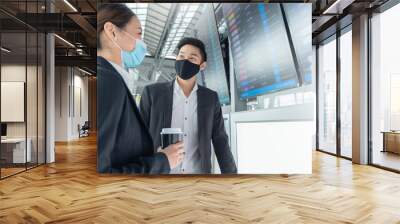 two asian businessman and businesswoman with face mask protection in international airport terminal conversation near information board business concept Wall mural