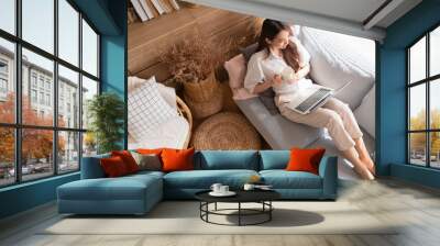 young attractive asian female working at home hand use laptop checking search schedule working process planning report with leisure relax on sofa in living room with morning light peaceful moment Wall mural