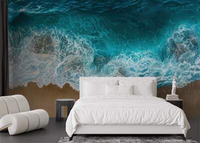 Observe the rhythmic patterns of ocean waves rolling onto a sandy shore from an aerial perspective Wall mural