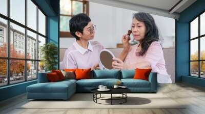 An elderly woman happily spends her free time make up with friends in the living room. Wall mural