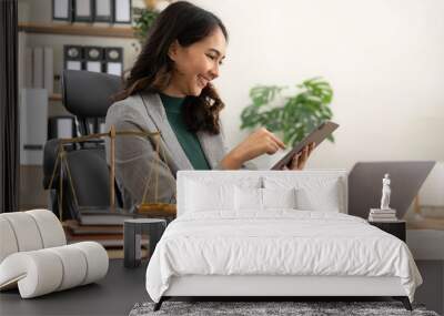 asian woman lawyer working and judge in a courtroom the gavel, working with tablet and laptop and digital tablet computer on white table Wall mural