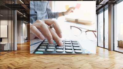 businessman or accountant hand working on calculator to calculate financial data report, accountancy document and laptop computer at office Wall mural