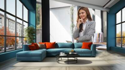 Confident Young Businesswoman Standing at Her Desk in Modern Office Environment Wall mural