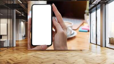 Mockup image blank white screen cell phone.women hand holding texting using mobile on desk at home office. Wall mural