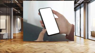 Mockup image blank white screen cell phone.women hand holding texting using mobile on sofa Wall mural