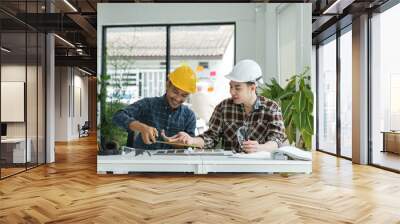 Two Male Engineer collaboration in a Modern Office Environment, Wearing Safety Helmet and Working on a Project with Blueprint and Tools, Surrounded by Natural Light and Greenery Wall mural