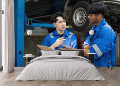 Young Man Repairing Car at Auto Repair Shop with Mechanic, Discussing Vehicle Maintenance in Professional Garage Setting Wall mural