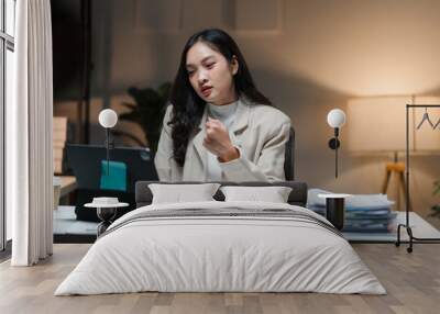 Focused Determination: A young businesswoman works late into the night, engrossed in her tablet, showcasing the dedication and drive it takes to succeed in today's world.   Wall mural