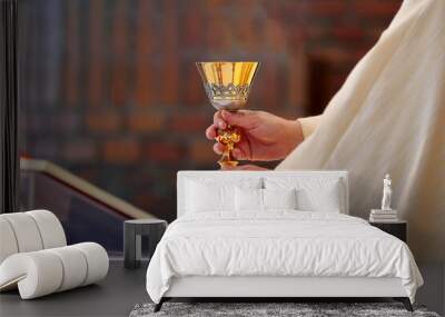 Chalice in the hands of the priest on the altar during the celebration of the mass Wall mural