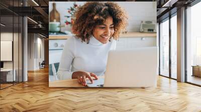 Concentrated and excited dark skinned young buyer with trendy hair looks in laptop smiles and enjoys online shopping closeup Wall mural