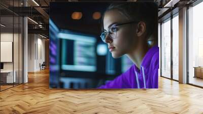 Focused young woman in glasses coding on computer screen in dark room, cybersecurity or software development concept Wall mural