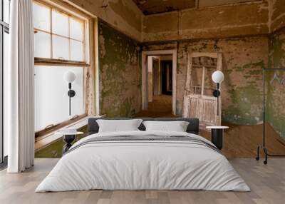 Abandoned industrial building in the old mining town of Kolmanskop in Namibia with crumbling walls and sand invading the interior Wall mural