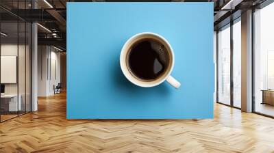 A cup of coffee seen from above on a plain blue table top. Wall mural