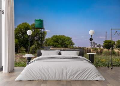 Plastic water tower in the field with a round cement and corrugated iron dam.  Wall mural