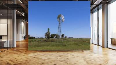 Wind pump also known as a wind mill in a rural area, being it is a green plastic storage tank to contain the water that is extracted from the earth  Wall mural