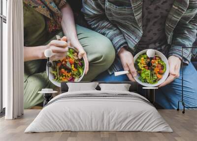 Couple eating healty salad at home on the sofa Wall mural