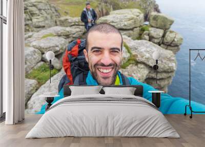 Man hiking and taking a selfie on top of cliffs Wall mural