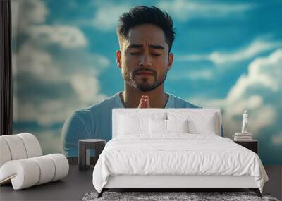 A young man praying in front of a beach. Wall mural