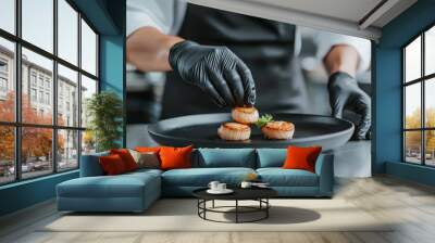 A chef in gloves placing a final touch on a dish of seared scallops, with the elegant dining room of the luxurious restaurant visible through glass walls. Wall mural