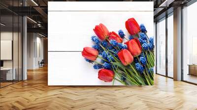 Bouquet of red tulips and blue muscaries flowers on white wooden background. Place for text. Wall mural