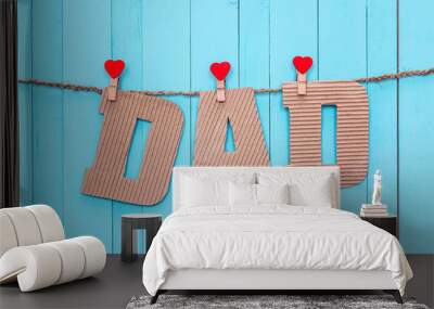 Cardboard letters DAD hanging on clothespins on a blue wooden ba Wall mural