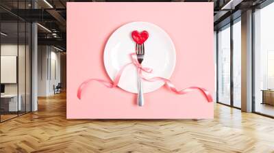 Fork with a heart on a plate on a pink table. Festive menu for Valentine's Day. T Wall mural