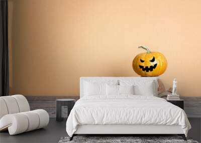 Wooden toy car with funny evil pumpkin on the roof on orange background. Space for text. Wall mural