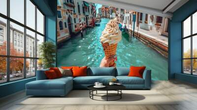  A person is holding a cone of ice cream in their hand. The ice cream is placed on a boat in a city in europe Wall mural