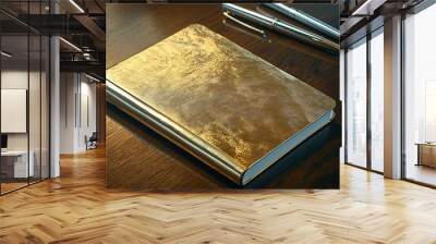 A gold and silver metallic notebook with matching pens placed on a dark wooden desk Wall mural