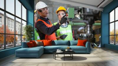 Asian foreman manager showing case study of factory machine to two engineer trainee young woman in protective uniform. teamwork people training and working in industrial manufacturing business Wall mural