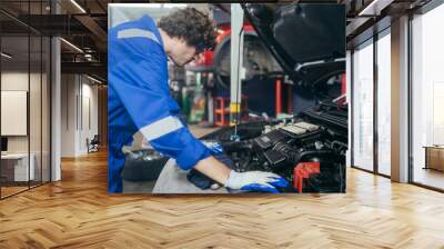 Caucasian auto mechanic man checking and repairing car radiator bonnet in automotive in garage at auto repair shop, motor technician working after vehicle service maintenance concept Wall mural