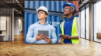 Logistic foreman discussing business work with African contractor worker at container warehouse or construction site. Manager using digital tablet. Wall mural