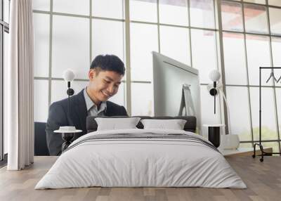 Portrait of Asian happy employee man or business manager using smartphone searching information on the internet at office desk. social media communication and working on project, copy space Wall mural