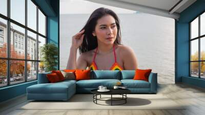 Young Asian beautiful woman in bikini looking sexy. hair blowing in wind on tropical beach in summer weather. travel and lifestyle concept Wall mural