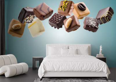 Assorted chocolate pralines floating on blue background Wall mural