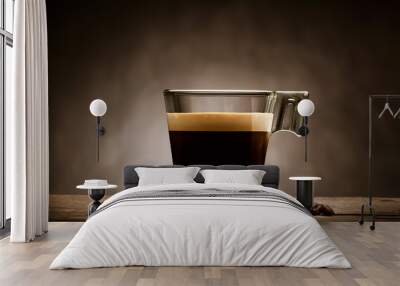 Black coffee in glass cup with coffee beans on wooden table Wall mural