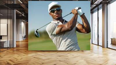 handsome golfer sport man with hat  and a beautiful shirt, swinging a club during a sunny day on the course. Wall mural