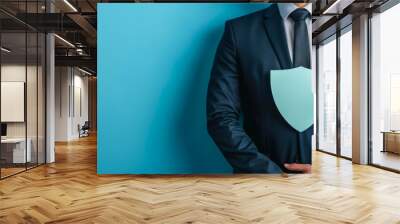 Businessman in suit holding a shield symbolizing protection and security over a blue background. Wall mural