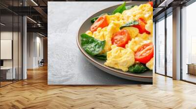 Delicious fluffy scrambled eggs with fresh tomatoes and spinach, perfect for a healthy breakfast or brunch dish. Wall mural