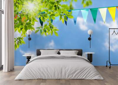 colorful pennant string decoration in green tree foliage on blue sky, summer party background templa Wall mural