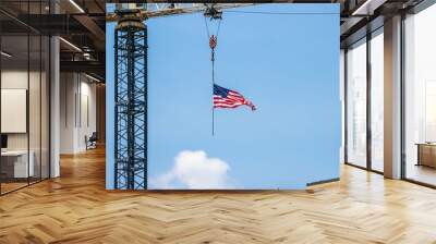 American flag hanging from a construction crane against a clear blue sky. Wall mural