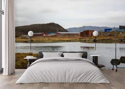 Beautiful green beach by pond with rural cabins and hills under misty sky in Murmansk, Russia Wall mural