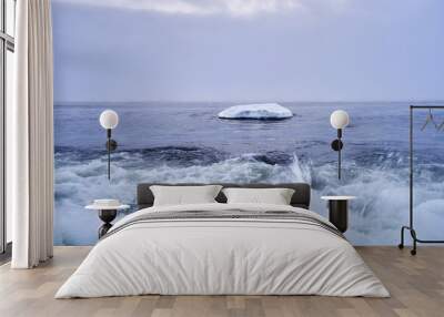 beautiful winter landscape featuring the cloudy sky over a floating iceberg and sea waves Wall mural