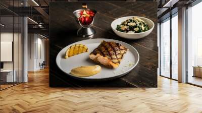 Closeup of a plate of fish stake with lemon on a wooden table Wall mural