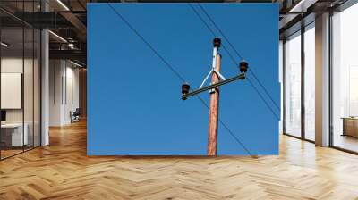 High-voltage power pole with several electric wires against a bright blue sky Wall mural