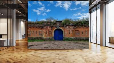 Majestic view of historical Fort 3 in Belgium, with a blue door against a cloudy blue sky Wall mural